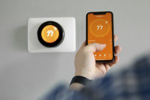 person uses a cell phone to set their thermostat